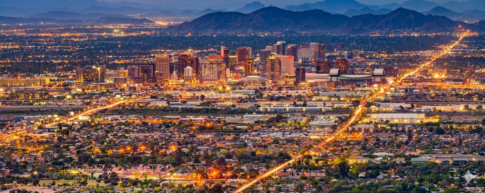A sprawling nighttime aerial view of the Phoenix city skyline and surrounding mountains. Acuity Health Solution.